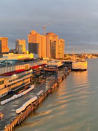 Buildings by river against sky in city