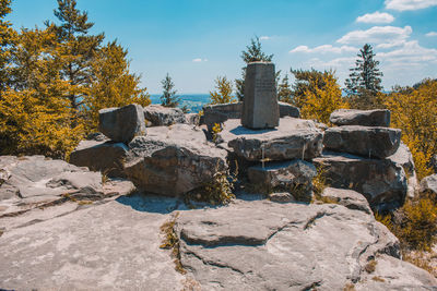 Rocks by trees against sky