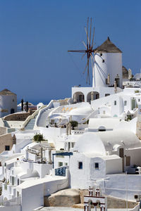 Traditional windmill by buildings against sky