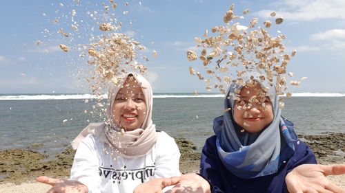 Portrait of friends enjoying at beach against sky