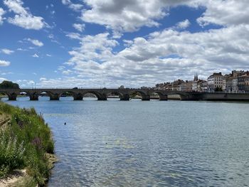 Bridge over river in city against sky