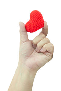 Close-up of hand holding heart shape against white background