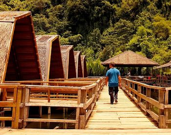 Rear view of man walking on footbridge