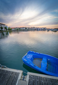 Boats moored in lake against sky during sunset