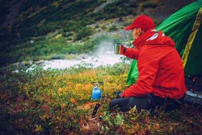 Man drinking coffee by tent at campsite