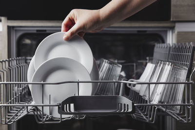 Woman puts a plate in the dishwasher or takes from it. housewife does her housework
