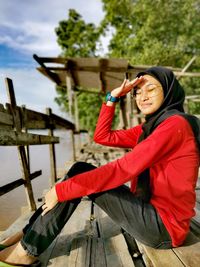 Teenage girl looking away while sitting on wood