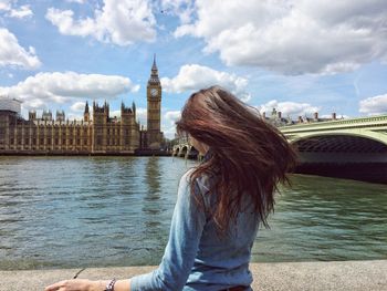 Rear view of a woman with river against clock tower