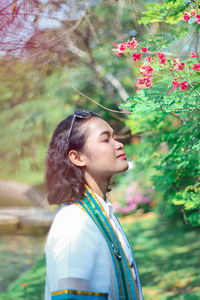 Side view of woman standing by branches at park