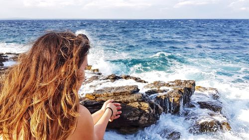 Rear view of woman looking at sea against sky