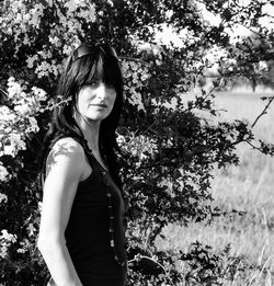 Portrait of beautiful woman standing by plants on field 