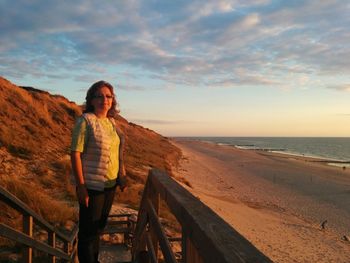 Woman standing on beach at sunset