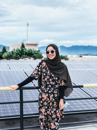 Young woman wearing sunglasses standing against sky