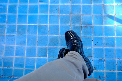 Low section of man sitting at empty swimming pool