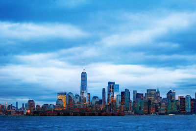 Sea by modern buildings against sky in city