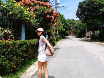 Full length portrait of young woman standing by plants