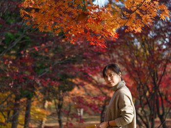 Portrait of man standing by tree during autumn