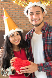 Man giving heart shape gift to girlfriend during christmas party