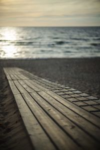 Surface level of pier on beach against sky