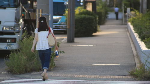 Rear view of woman walking on road in city