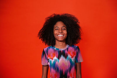 Portrait of smiling young woman against red background