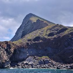 Scenic view of sea by rock formation against sky