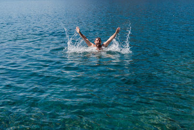 Man with arms raised swimming in sea