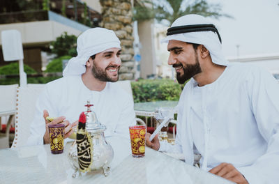 Smiling business people having discussion while sitting at cafe