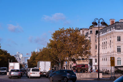 Cars on street by buildings in city against sky