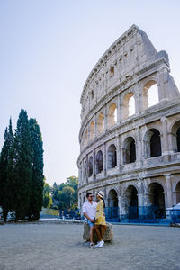 People in front of historical building against clear sky