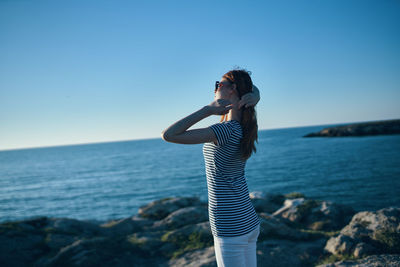 Woman standing by sea against clear blue sky