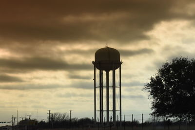 Silhouette of water tower against cloudy sky