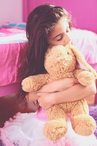 Close-up of girl embracing toy animal at home