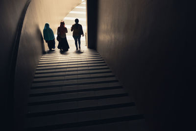 Rear high angle view of three people walking down stairs