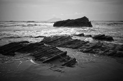 Rock formation on shore against sky 