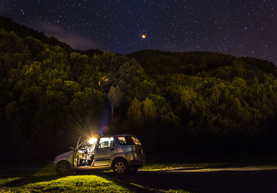 Cars on road at night against sky full of stars 