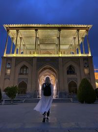 Full length rear view of woman standing against building