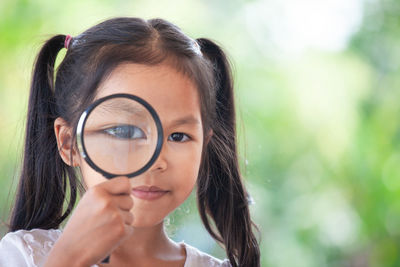 Portrait of smiling girl looking through magnifying glass