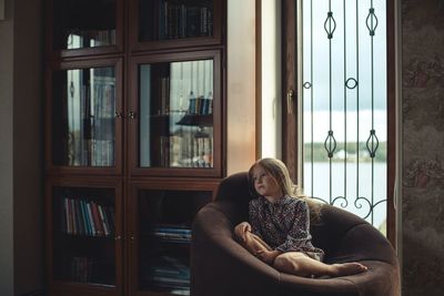 Portrait of woman sitting by window at home