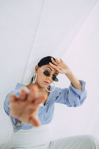 Young woman wearing sunglasses sitting on floor