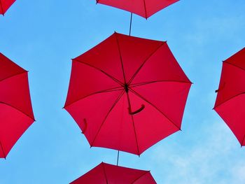 Low angle view of red umbrellas hanging against sky