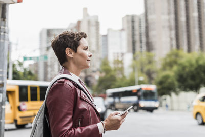 Side view of man using smart phone on city street