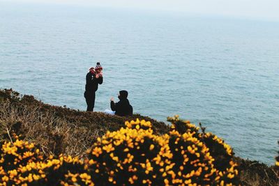 People standing on rock by sea against sky