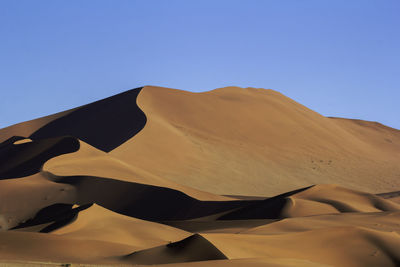 Scenic view of desert against clear blue sky