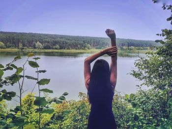 High angle view of woman standing by river against clear sky