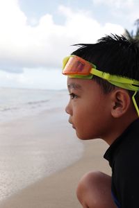 Portrait of boy wearing sunglasses on beach against sky