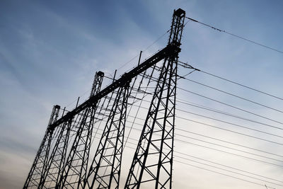 Low angle view of electricity pylons against sky