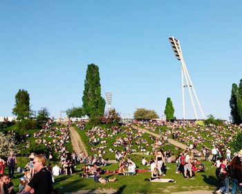 Group of people relaxing on grassland against clear sky