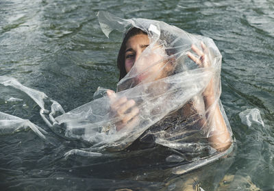 Portrait of girl amidst plastic in sea