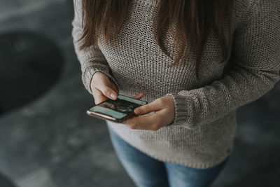 Midsection of woman holding mobile phone